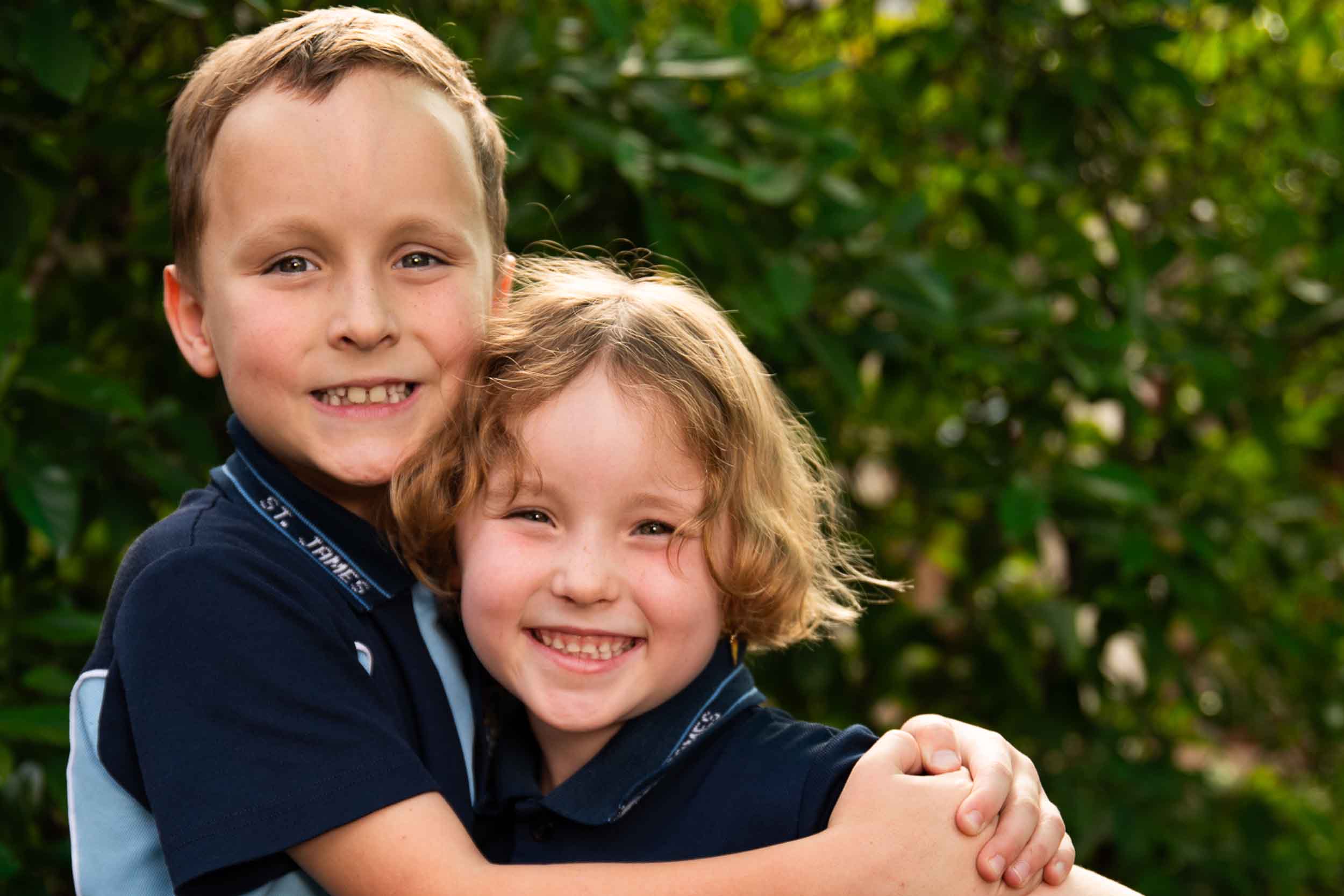 Two primary aged students with their arms around each other and smiling.