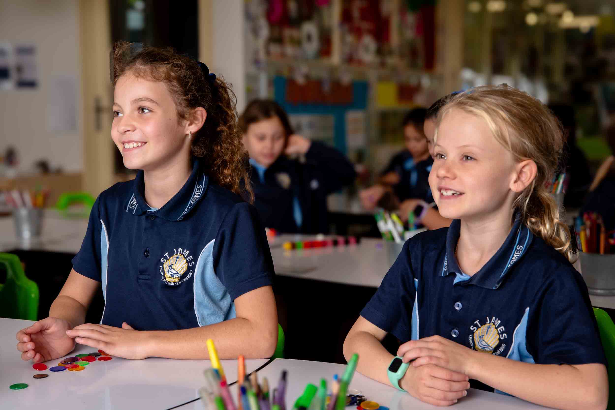 Two students sitting at a desk, looking ahead and smiling.