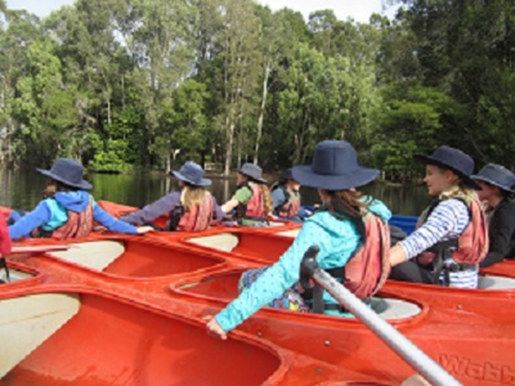 7 people sitting in canoes floating on the water.